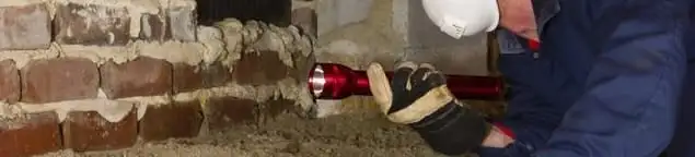 Pest control technician inspecting a crawl space for ant activity and entry points in Nashua, NH