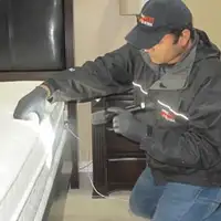 Bed bug inspection technician checking a mattress and bed frame for signs of infestation in Nashua, NH